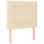 Cremefarbenes Boxspringbett mit Stoffbezug und Kopfteil, 120x200 cm.