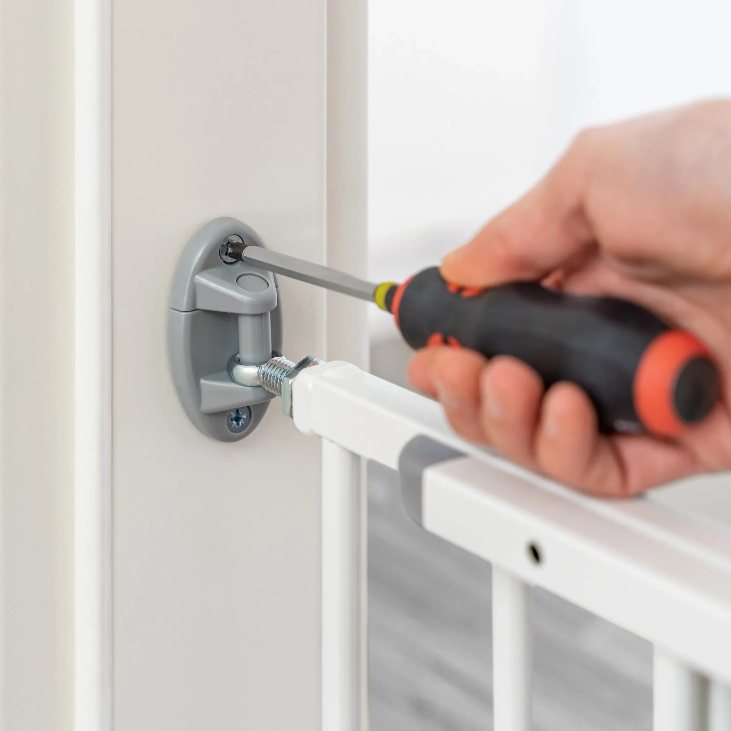 Montage des weißen Schraubgitters Simple-Lock: Hand schraubt Gitter an Türrahmen.