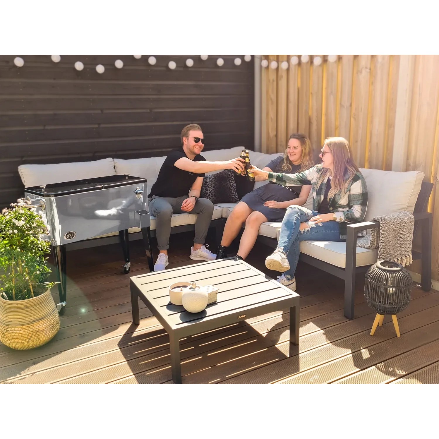 Axi Kühlwagen Retro Edelstahl 76 l mit feiernden Personen im Garten.