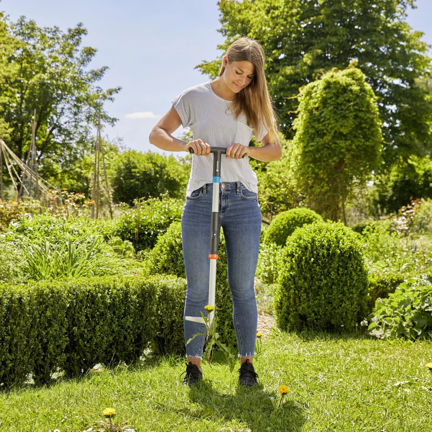 Frau benutzt Gardena Unkrautstecher im Garten zur Unkrautentfernung.