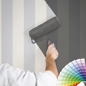 Überstreichbare Vliestapete mit Blockstreifen in Grau/Weiß wird mit Farbroller gestrichen.