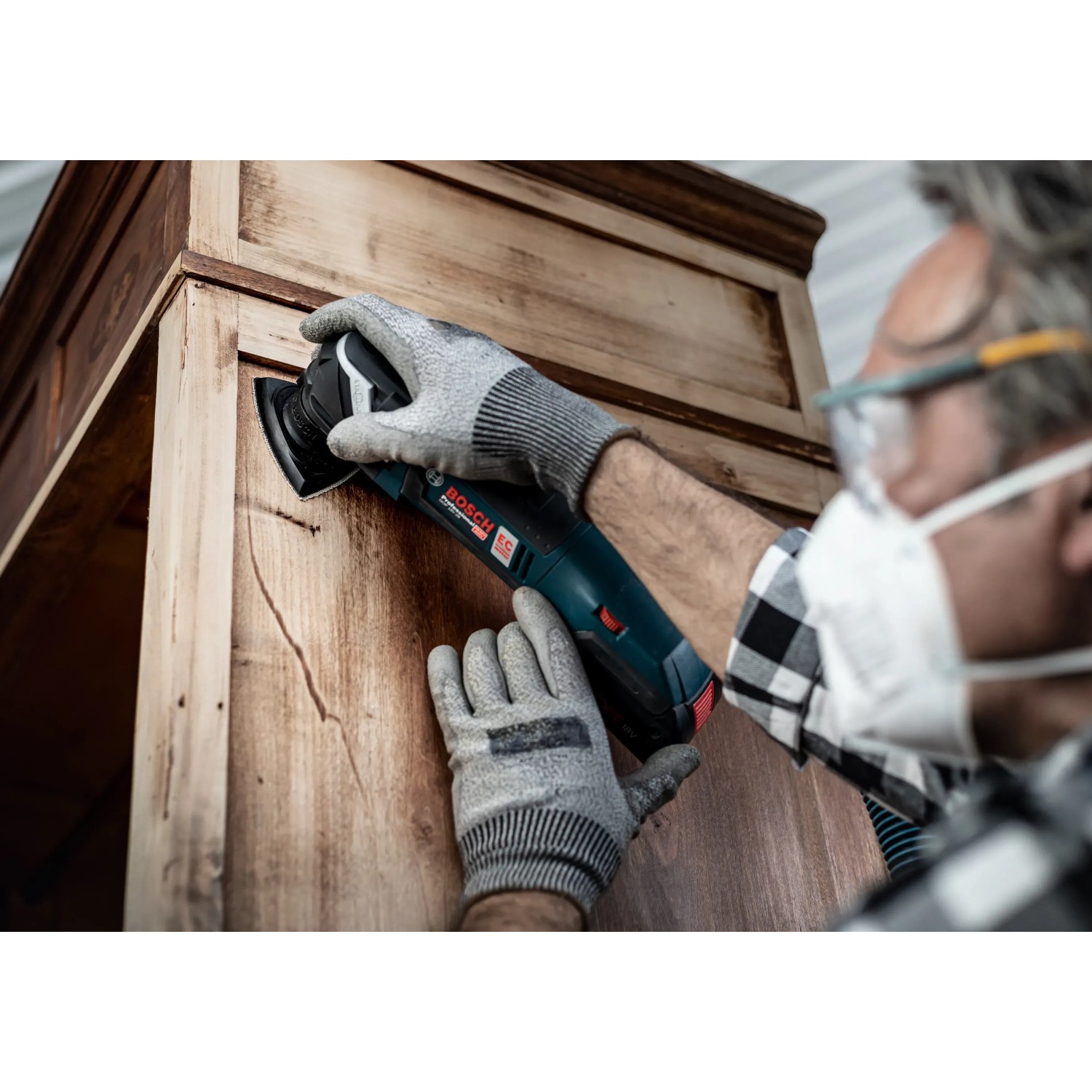 Mann schleift Holzschrank mit Bosch Expert Deltaschleifer und Schleifblatt C470 K240.