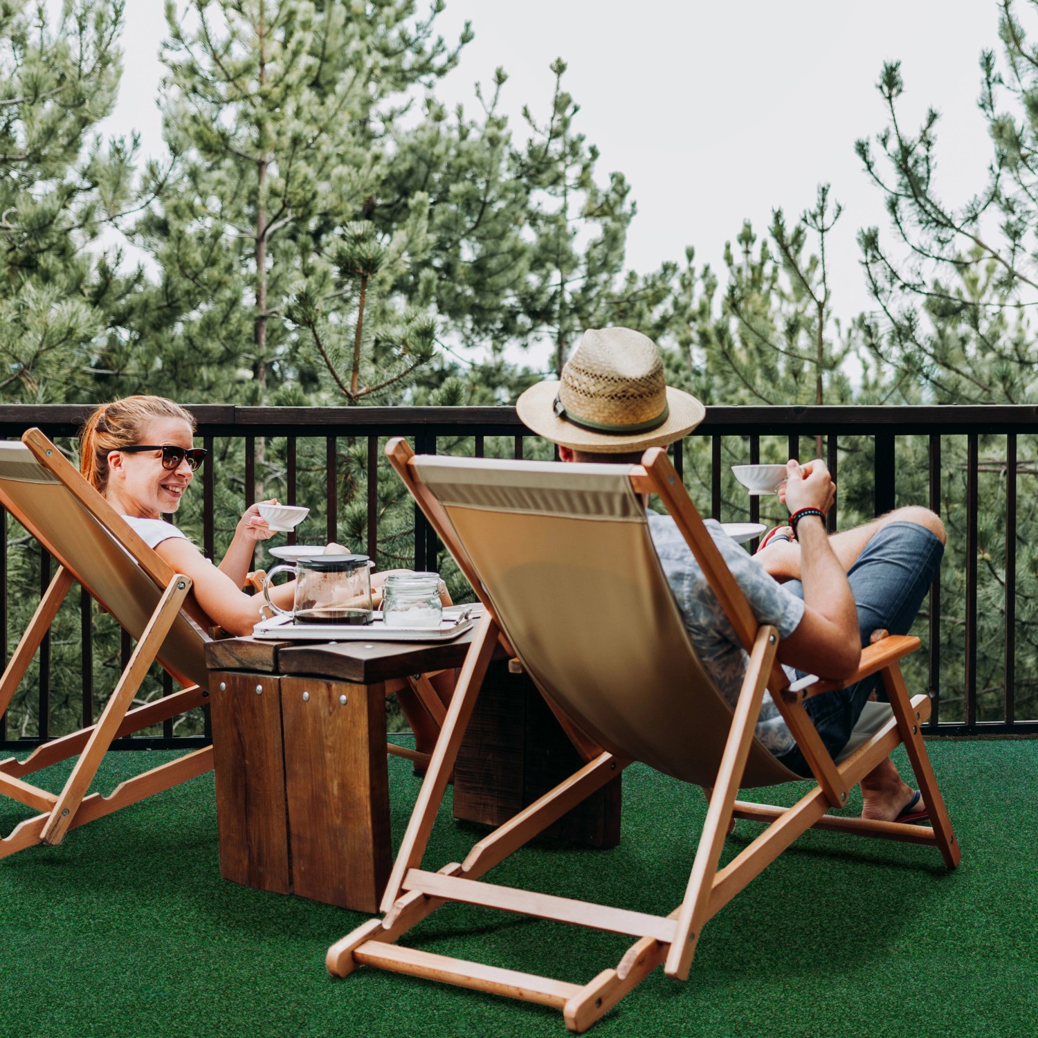 Szene mit grünem Primaflor Rasenteppich: Paar entspannt auf Balkon mit Kunstrasen.