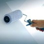 Hand streicht Wand mit LUX Farbroller 25 cm mit Softgriff in Schwarz-Blau.