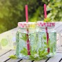 Zwei Gläser Waldmeister-Getränk mit Strohhalm und Waldmeister-Topf im Hintergrund.
