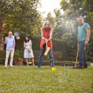 Personen spielen Krocket mit dem Relaxdays Krocketspiel im Garten. Holzschläger und bunte Kugeln.