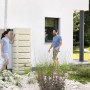 4rain Wandtank Slim Stone Decor 500 l in Sandbeige mit Steindekor vor Hauswand.