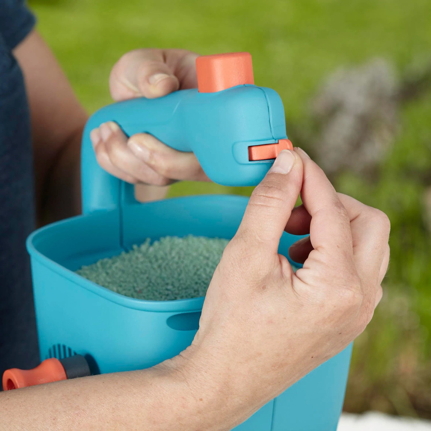 Gardena Handstreuer M, blauer Streuwagen mit Füllung und Hand, Dosierung wird eingestellt.