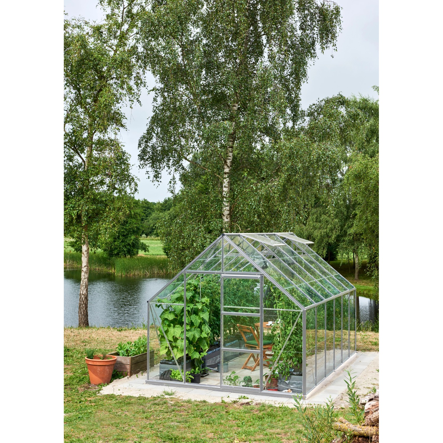 Halls Gewächshaus Universal 128 aus Alu mit 9,9 m² und Fundamentrahmen im Garten.