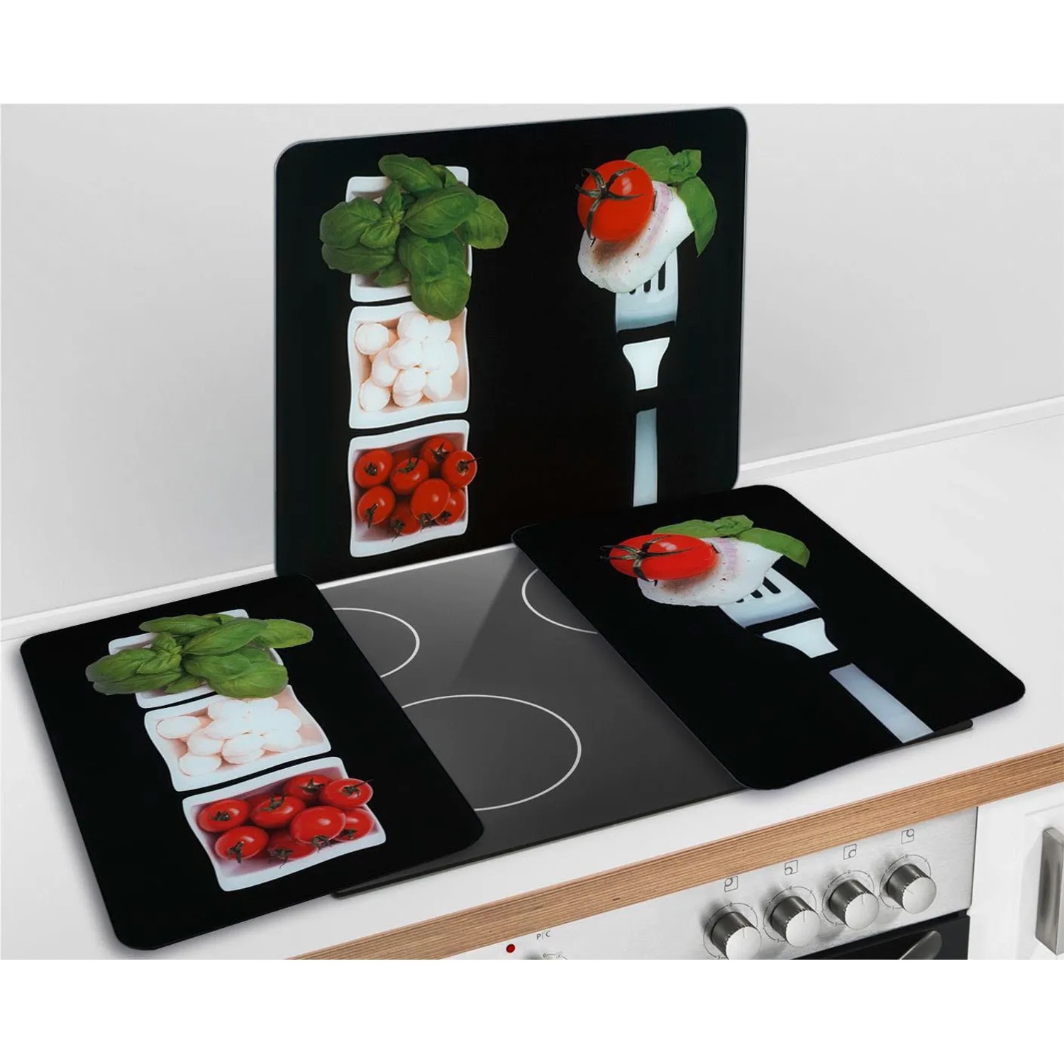 Wenko Herdabdeckplatten Caprese 2er Set mit Tomaten, Mozzarella und Basilikum auf schwarzem Hintergrund.