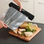 Wenko Folienspender Perfect Cutter Black Outdoor Kitchen, Folie wird über Käse gezogen.