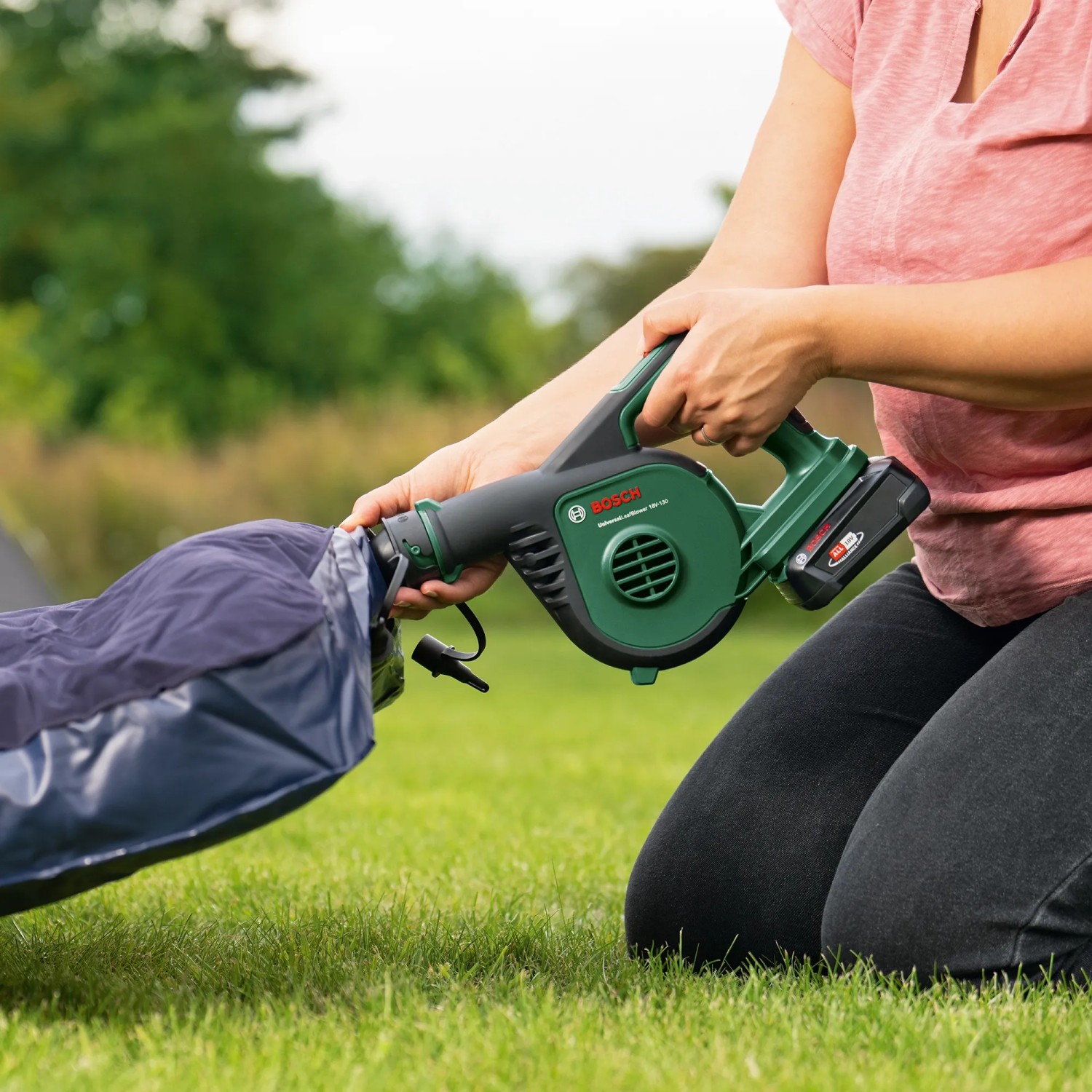 Frau nutzt Bosch Akku-Laubbläser UniversalLeafBlower 18V-130 zum Aufblasen einer Luftmatratze.