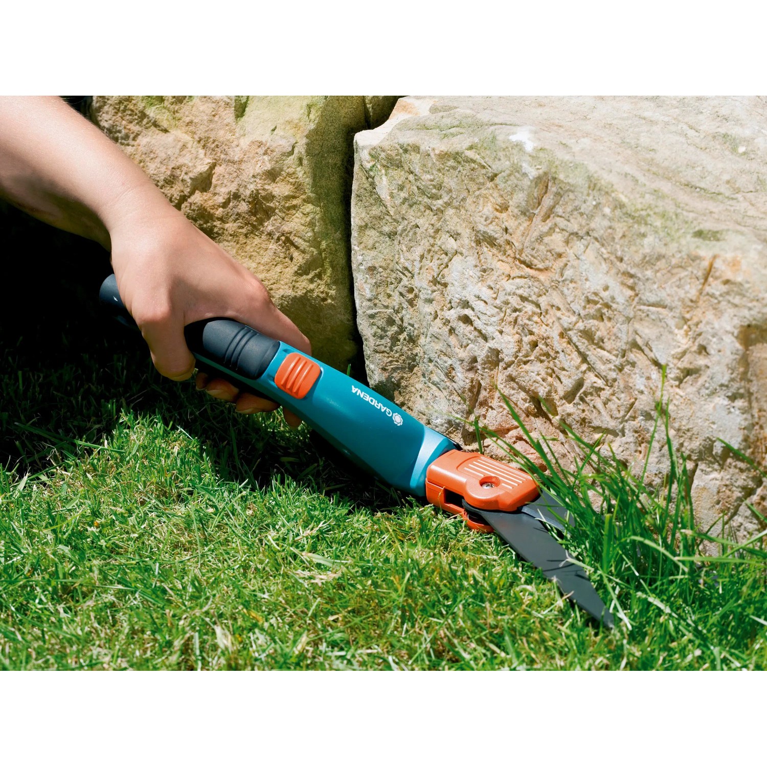 Gardena Comfort Grasschere beim Rasenkantenschneiden nahe eines Steins.
