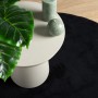 Schwarzer, runder Kurzflorteppich OVIEDO (Ø 200 cm) neben einem Beistelltisch.