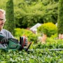 Mann schneidet Hecke mit Bosch Elektro-Heckenschere UniversalHedgeCut 60.