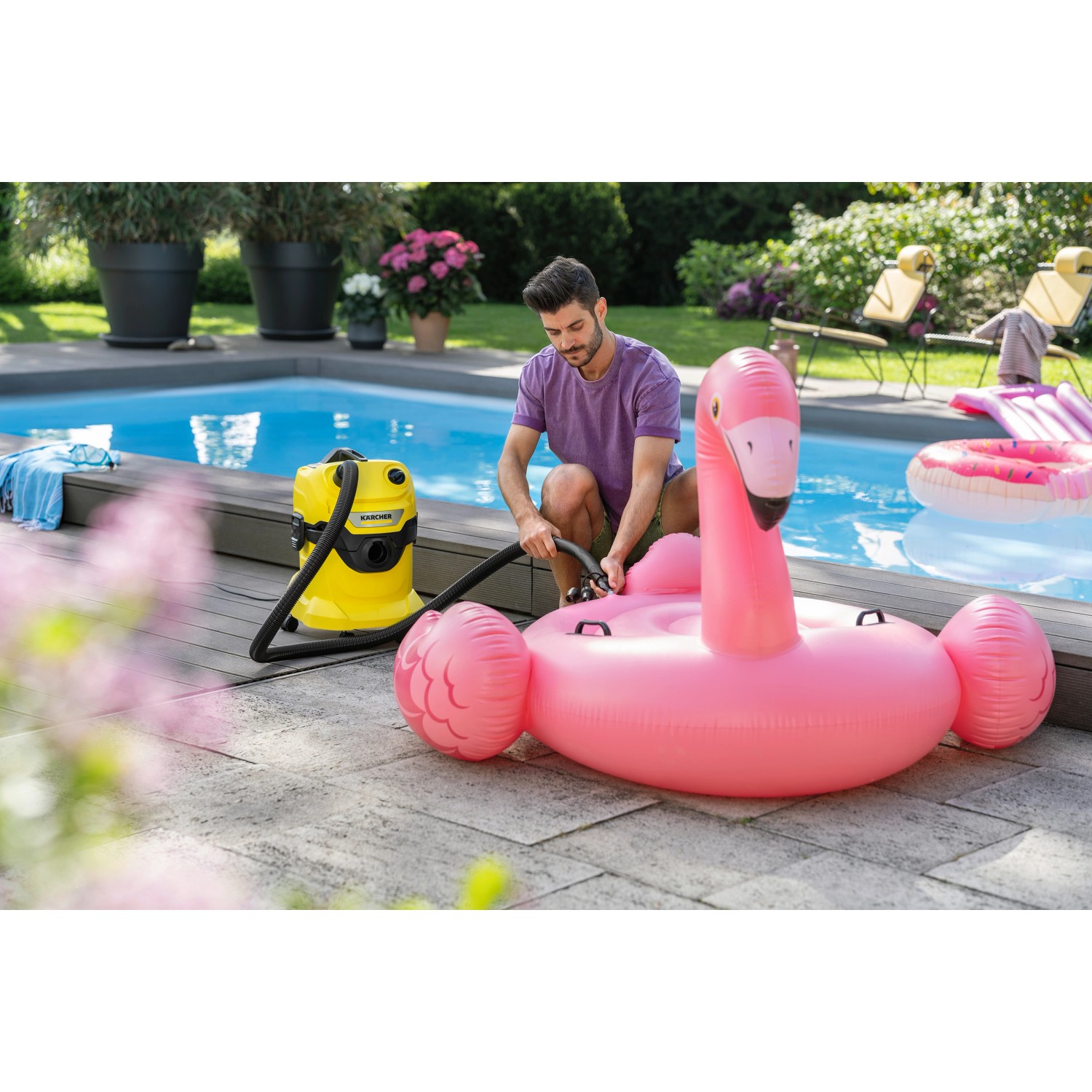 Kärcher Blasadapterset im Einsatz: Mann pumpt rosa Flamingo Luftmatratze mit Nass-/Trockensauger am Pool auf.
