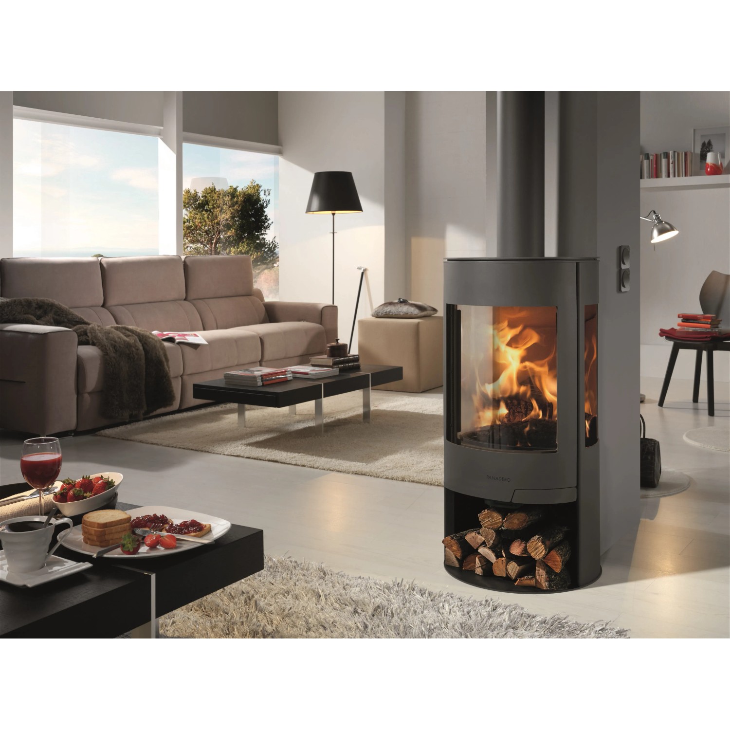 Panadero Suerte Kaminofen, 8 kW, Stahl schwarz metallic im Wohnraum mit Holzscheiten.