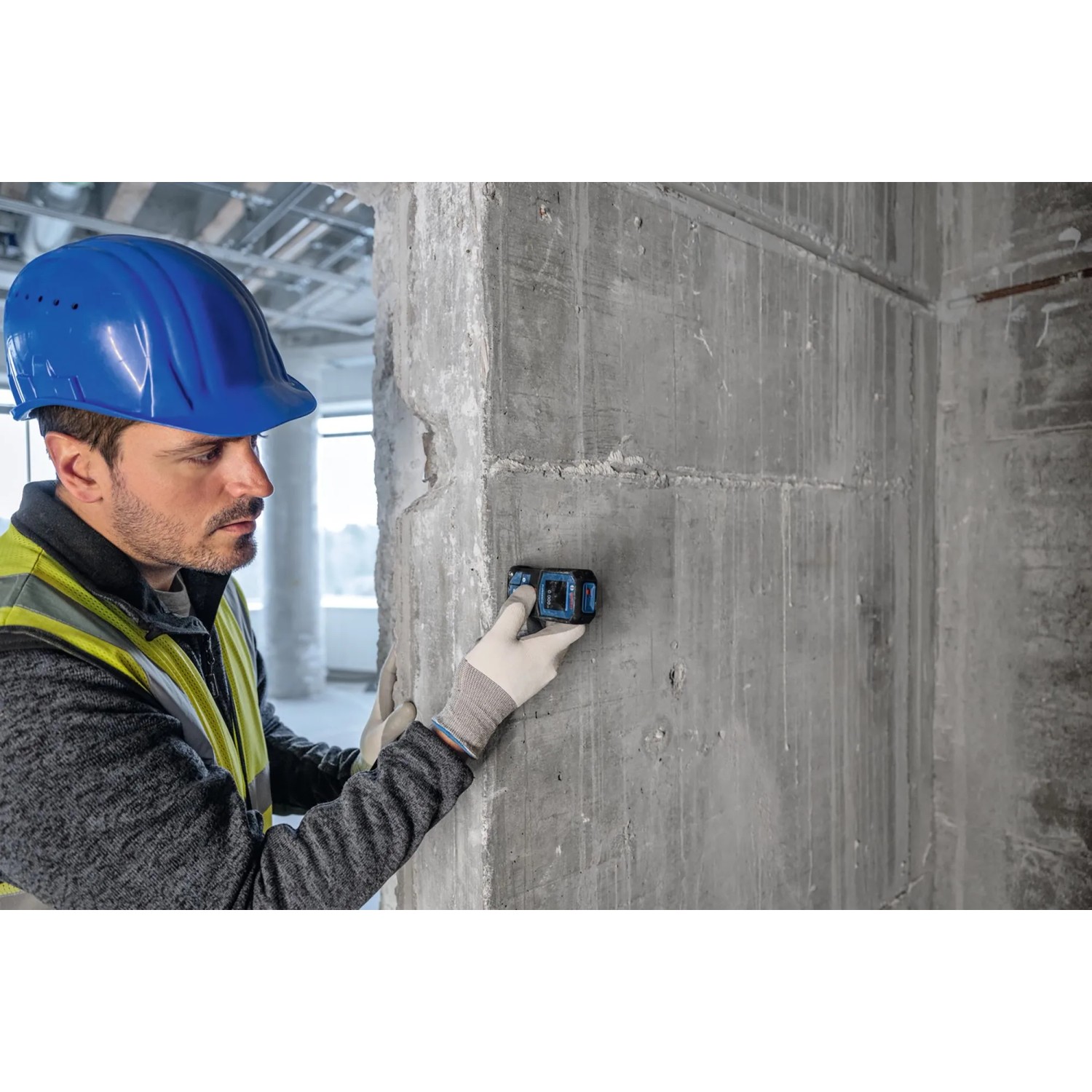 Handwerker misst mit Bosch Professional Laser-Entfernungsmesser GLM 40-31 eine Betonwand.