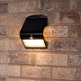 Schwarze LED Solar-Außenleuchte mit Sensor an einer Backsteinwand. Flutlicht mit 400 Lumen.