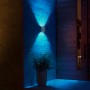 Silberne Philips Hue Resonate LED-Außenwandleuchte mit blauem Lichtschein an einer Hauswand.