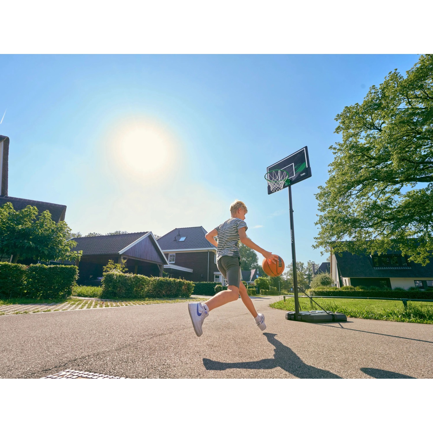 Junge spielt mit Salta Basketballständer Forward (108x362cm) im Garten.