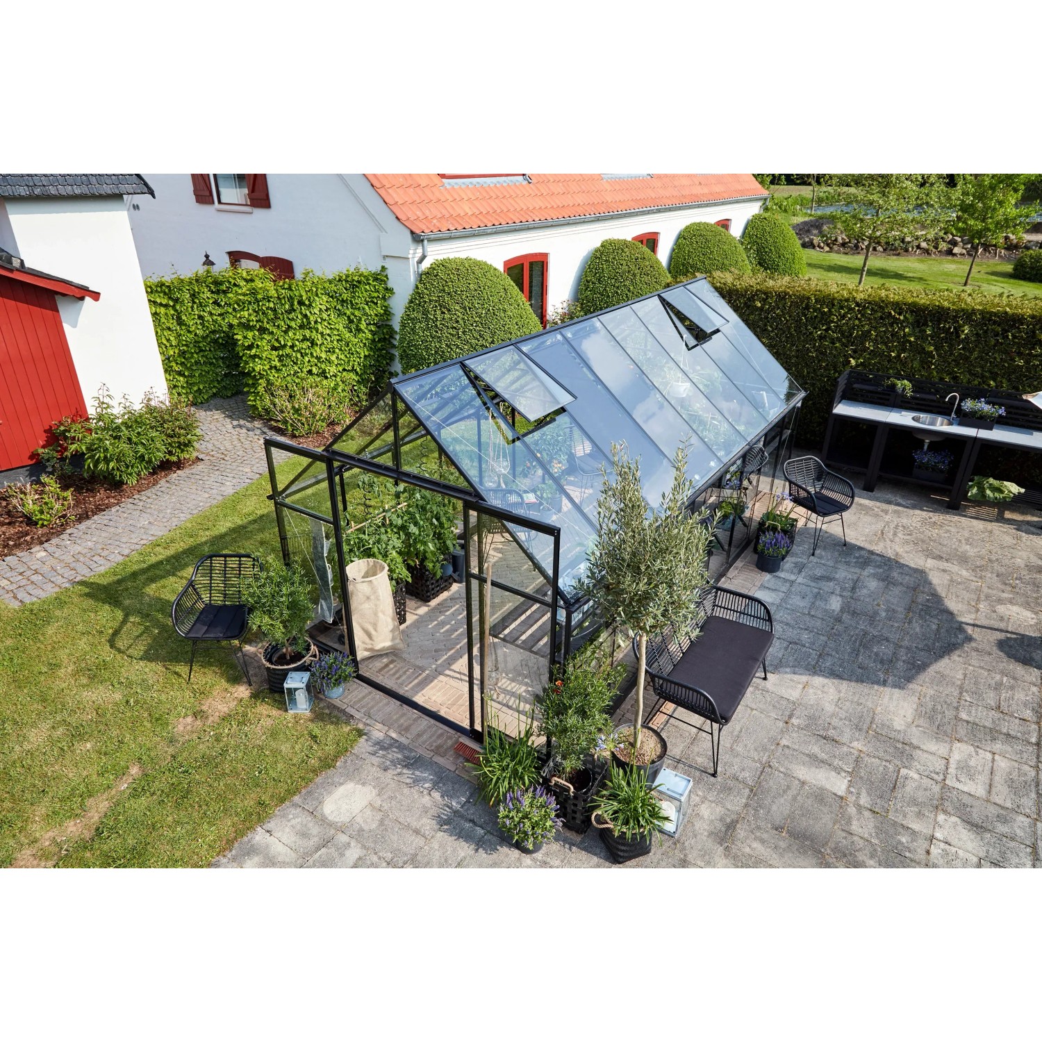 Schwarzes Halls Gewächshaus Qube+ 816 mit geöffneten Fenstern im Garten.