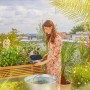 Frau bedient Gardena AquaBloom L Solar-Bewässerung im Garten.