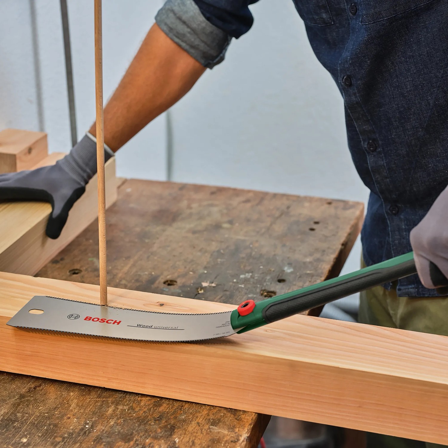 Bosch Japansäge Ryoba beim Sägen von Holz. Zugsäge mit grünem Griff.