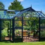 Juliana Gewächshaus Orangerie 15, schwarz-anthrazit, mit Pflanzen und Sitzgruppe im Garten.