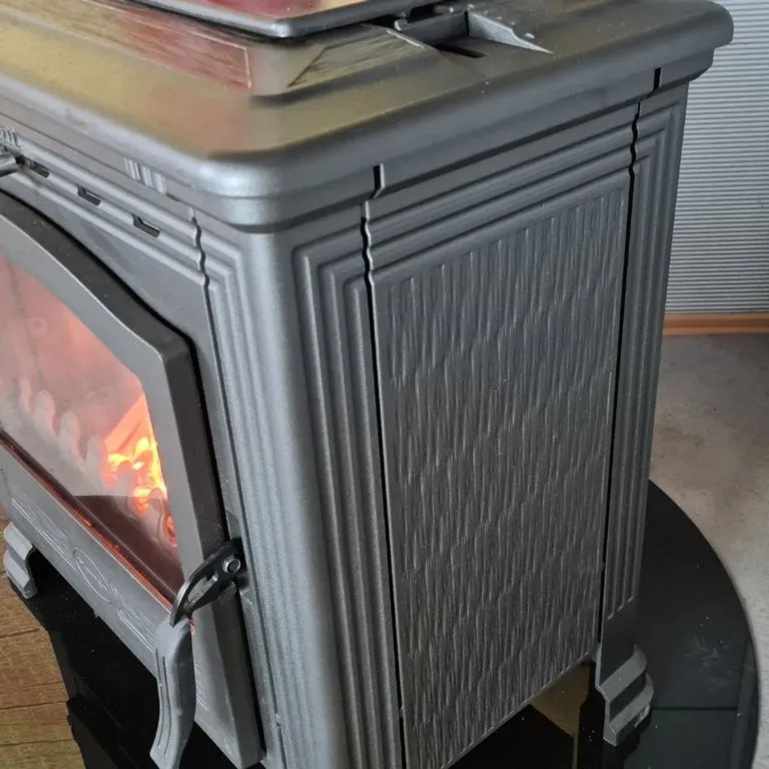 Plamen Gusskaminofen Tena mit Herdplatte, Detailansicht. Kaminofen aus Gusseisen mit Feuer.