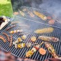 Char-Broil Holzkohlegrill L mit Grillgut: Würstchen, Maiskolben und Spieße auf dem Rost.