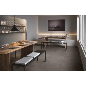 Verlegtes, dunkles Feinsteinzeug 75x75 cm in Zementoptik im Esszimmer mit Holztischen und Bänken.