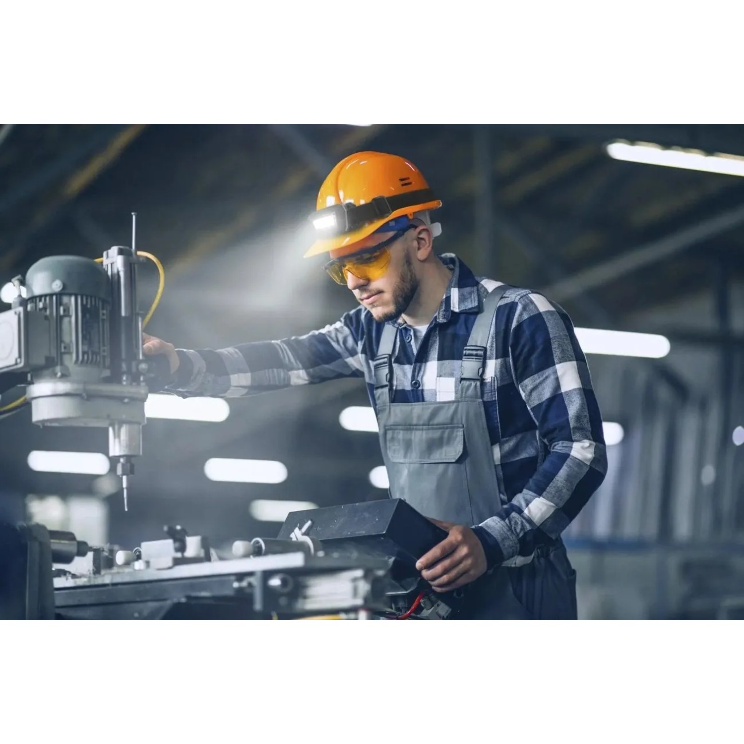 Handwerker mit Westfalia LED Sensor-Kopfleuchte (schwarz) bei der Arbeit an einer Maschine.