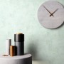 Moderne Vliestapete Perseus Mint mit Betonoptik an Wand, dekoriert mit Uhr und Vasen. Dekorative Tapete.