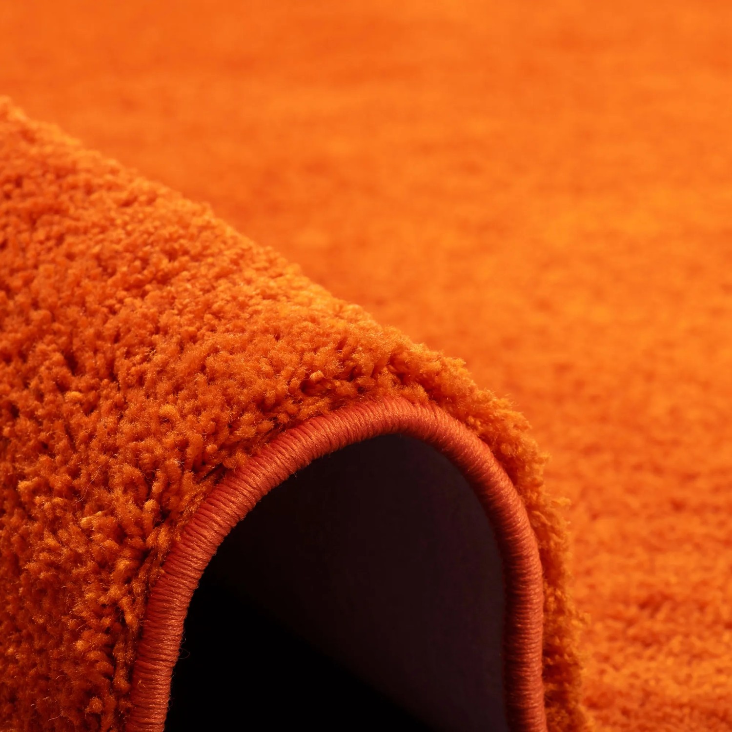 Detailaufnahme: Flauschiger, orangefarbener Snapstyle Hochflor Teppich Palace, 100x100 cm.