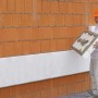 Mann verarbeitet WDVS Basis-Paket (160mm) an einer Hauswand. Vollwärmeschutz-System.