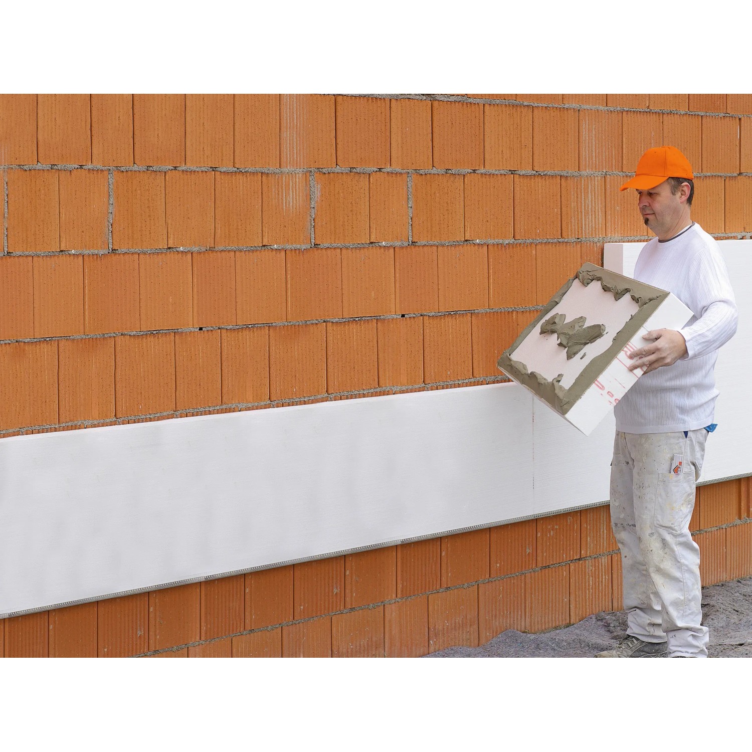 Mann verarbeitet WDVS Basis-Paket (160mm) an einer Hauswand. Vollwärmeschutz-System.
