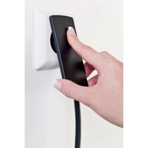 Hand steckt schwarzen Evoline Plug Flachstecker in weiße Steckdose. Ideal für platzsparenden Stromanschluss.