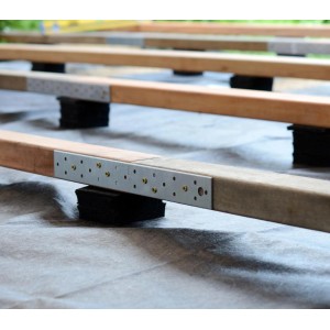 Terrassenpads 90x60x10 mm unter Holzbalken einer Terrassenkonstruktion.