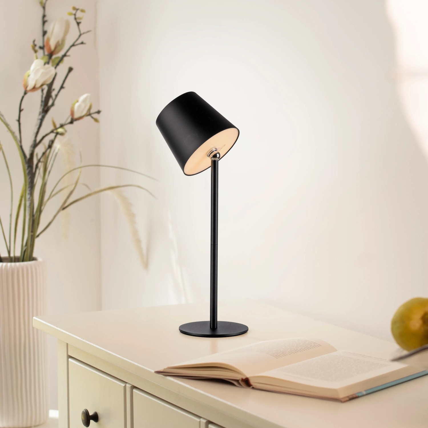 Schwarze Just Light Akku-LED-Tischleuchte Boteria, Ø 11 cm, Höhe 37 cm, auf einem Tisch.