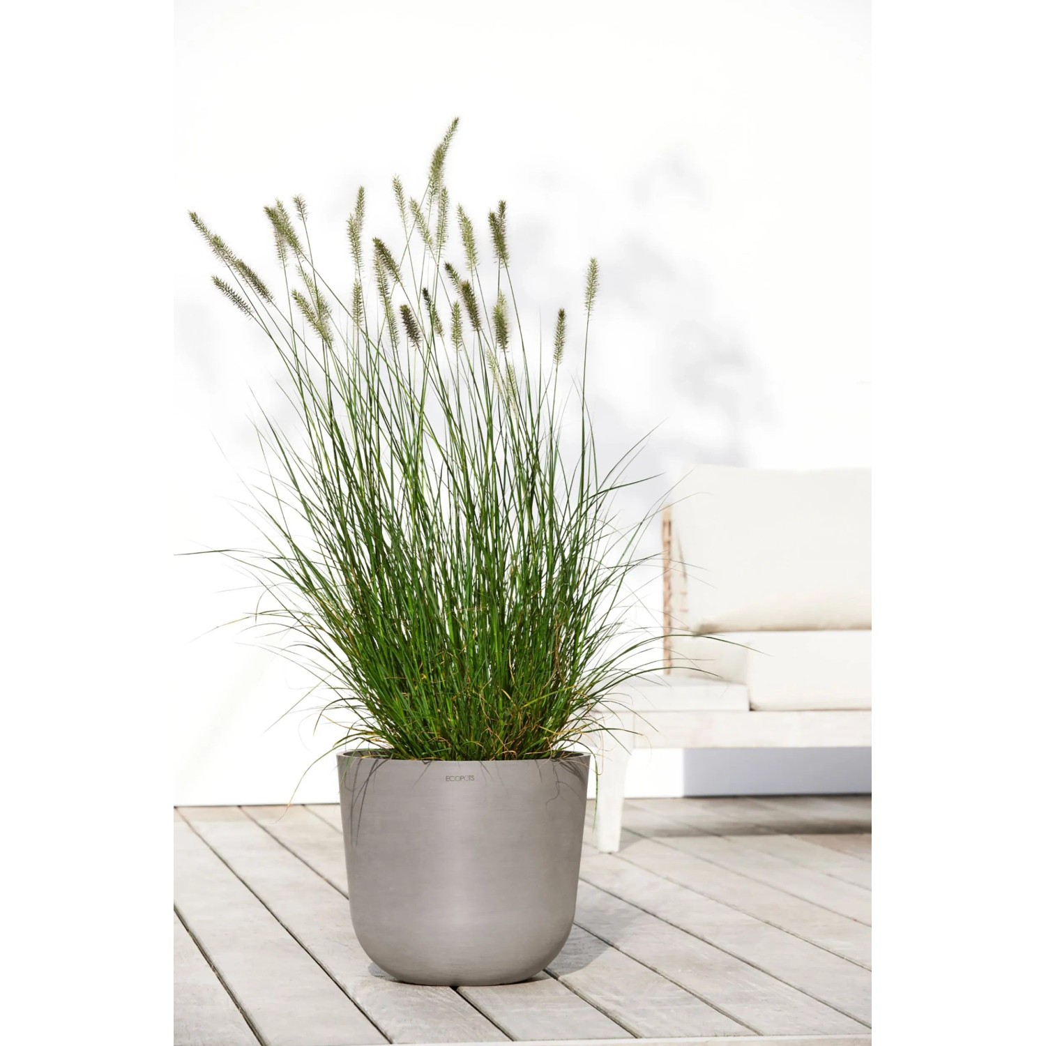 Ecopots Pflanztopf Oslo, braungrau, 35 cm, mit Ziergras auf einer Holzterrasse.