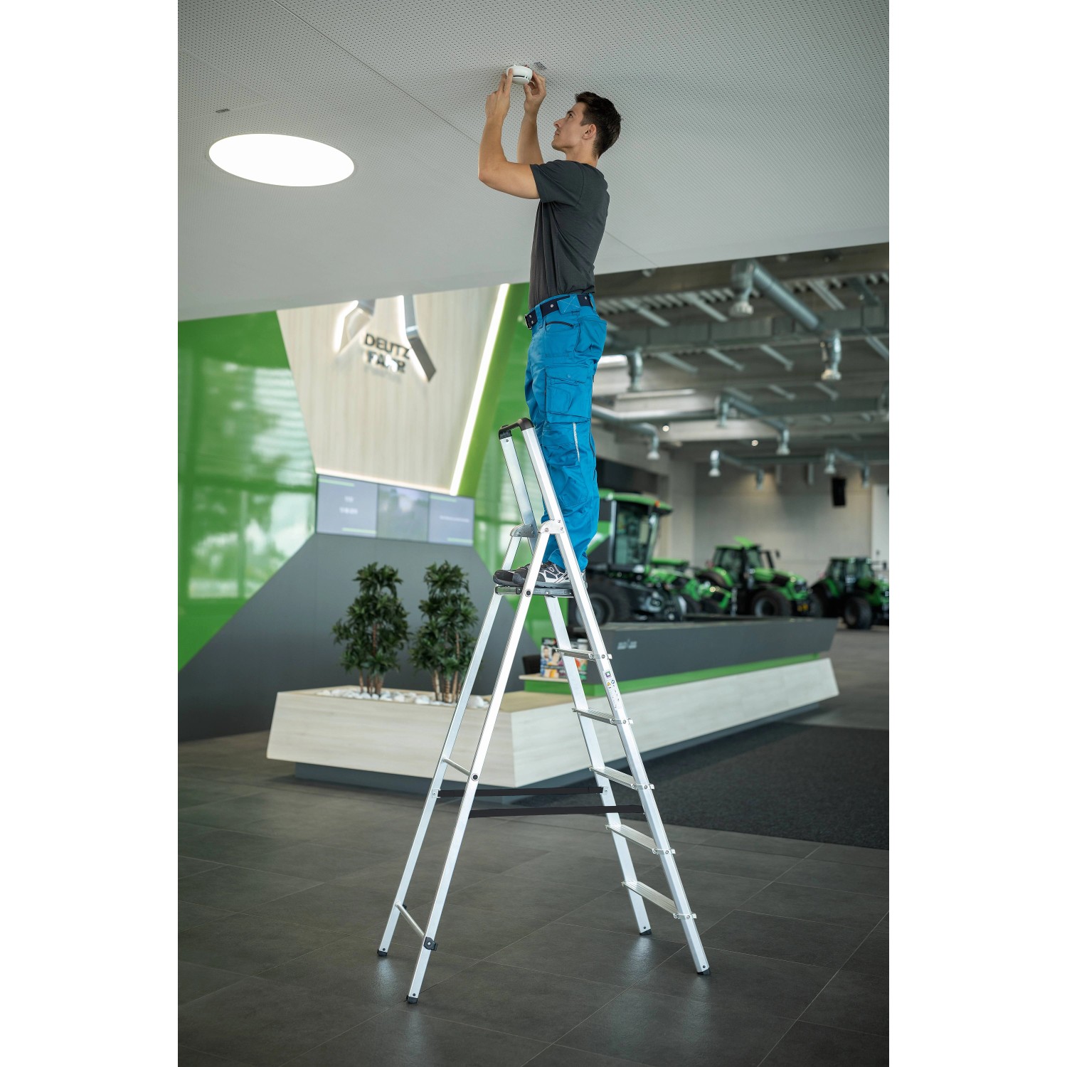 PROREGAL Stufen-Stehleiter mit 3 Stufen im Einsatz, Person montiert Lampe.