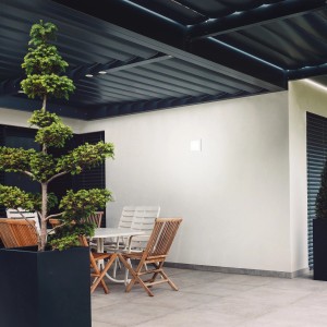 Eckige, weiße Brilo LED-Außenleuchte Frankfurt an Hauswand über Terrasse mit Sitzgruppe.