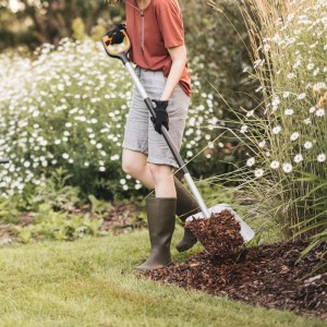 Frau hantiert mit Fiskars Xact Schaufel im Garten. Ideal für Bodenbearbeitung und zum Heben von Schüttgut.