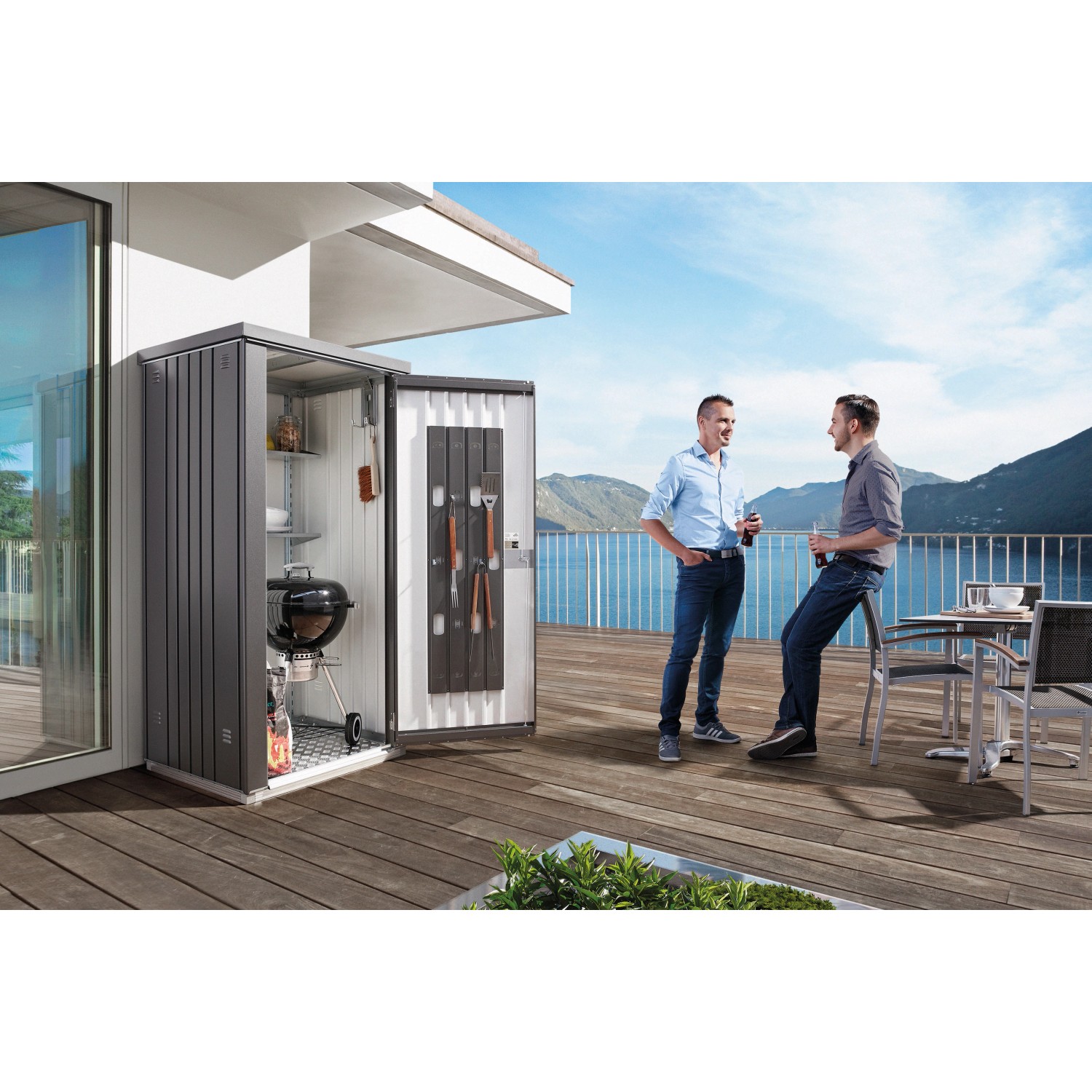 Offener, dunkelgrauer Biohort Geräteschrank Gr. 90 mit Grill und Zubehör, zwei Männer im Hintergrund.