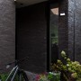 Schwarze Lutec LED Solar-Wandleuchte Tuda mit Bewegungsmelder an dunkler Hauswand.