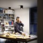 Schwarzer Philips Hue LED-Aufbauspot Pillar White Ambiance im Wohnraum, mit Mann am Schreibtisch.