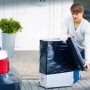 Mann verpackt Koffer mit schwarzer LUX Stretchfolie für Umzug oder Transport.
