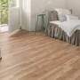 Verlegter Laminatboden Comfort Eiche Royal Elm 7 mm im Schlafzimmer mit Bett und geöffneter Balkontür.