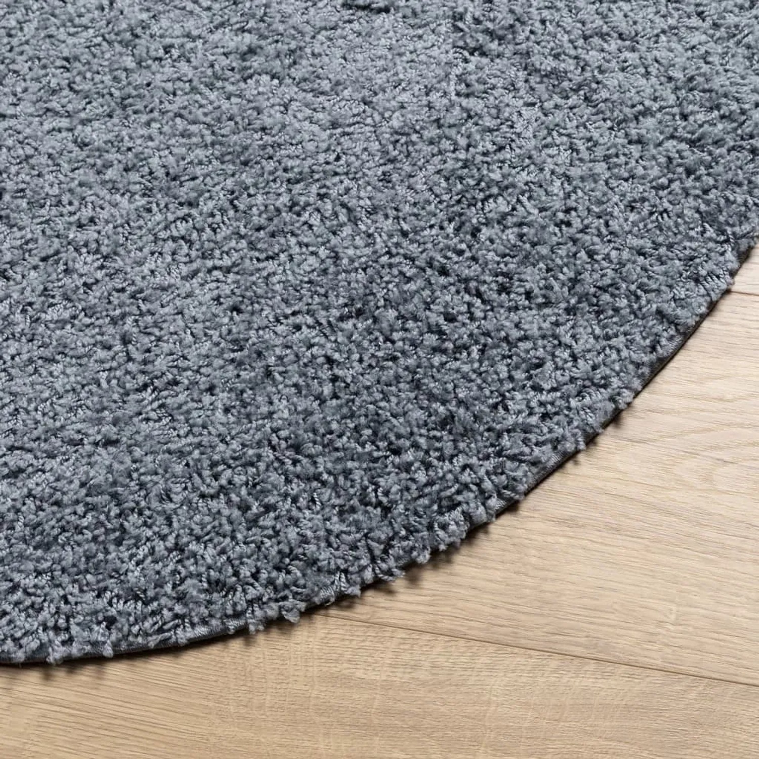 Blauer, runder Shaggy Teppich (200 cm) mit Hochflor auf hellem Holzboden.